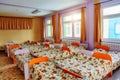 Many small beds with fresh linens in the kindergarten preschool empty bedroom interior for a comfortable afternoon sleep for Royalty Free Stock Photo