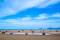 Many small fishing boats on sand beach during low tide with cloudy blue sky Royalty Free Stock Photo