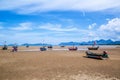 Many small fishing boats on sand beach during low tide with cloudy blue sky Royalty Free Stock Photo