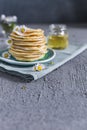 Many small pancakes with honey or syrup. Delicious traditional breakfast. Spring flowers as food styling in photography. Gray Royalty Free Stock Photo