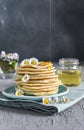 Many small pancakes with honey or syrup. Delicious traditional breakfast. Spring flowers as food styling in photography. Gray Royalty Free Stock Photo