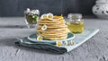 Many small pancakes with honey or syrup. Delicious traditional breakfast. Spring flowers as food styling in photography. Gray Royalty Free Stock Photo