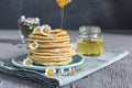 Many small pancakes with honey or syrup. Delicious traditional breakfast. Spring flowers as food styling in photography. Gray Royalty Free Stock Photo