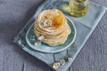 Many small pancakes with honey or syrup. Delicious traditional breakfast. Spring flowers as food styling in photography. Gray Royalty Free Stock Photo