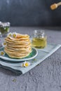 Many small pancakes with honey or syrup. Delicious traditional breakfast. Spring flowers as food styling in photography. Gray Royalty Free Stock Photo