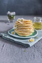 Many small pancakes with honey or syrup. Delicious traditional breakfast. Spring flowers as food styling in photography. Gray Royalty Free Stock Photo