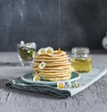 Many small pancakes with honey or syrup. Delicious traditional breakfast. Spring flowers as food styling in photography. Gray Royalty Free Stock Photo