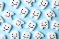 Many small plastic teeth with cute faces on color background