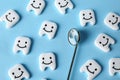 Many small plastic teeth with cute faces and mouth mirror on color background