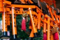 Many small red torii gates with prayers in japanese left by worshippers, hanging in Shinto Shrine in Kyoto.