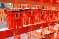 Many small Torii Gate hanging on red wooden hanger at Fushimi Inanari Shrine. People write blessings on amulets