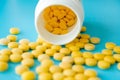 Many small yellow pills spilled out of a white jar on a blue background Royalty Free Stock Photo