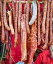 Many smoked Sausages and other pork meat products hanging from a stick at a food festival