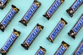 Many Snickers chocolate bars lies on pastel blue paper. Snickers bars are produced by Mars Incorporated. Snickers was created by