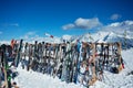 Many snowboards skis stand on alpine resort over mountains