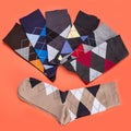 Many socks with color patterns of rhombuses lined on orange background