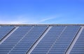 Many solar panels on steel roof of industrial building against blue sky background Royalty Free Stock Photo