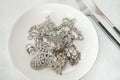 Many sparkling artificial diamond jewelery on a plate with a knife and fork. Close up