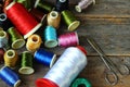 Spools of multicolored threads and scissors lying on wooden background Royalty Free Stock Photo