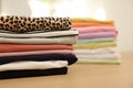 Many stacked clean clothes on wooden table, closeup