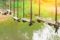 Many swings made of wooden board and tied with rope hang on cable over a small stream flowing through a tropical green rainforest