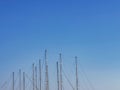 Many tall masts of many yachts isolated on clear sunny blue sky background. Blue sky with mast tops. Minimalist summer