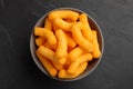 Many tasty cheesy corn puffs in bowl on black table, top view Royalty Free Stock Photo