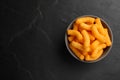 Many tasty cheesy corn puffs in bowl on black table, top view. Space for text Royalty Free Stock Photo