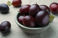 Many tasty ripe plums on light fabric, closeup