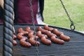 Many tasty sizzling sausages on the outside grill, springtime barbecue party in the yard, bbq concept, person in apron Royalty Free Stock Photo