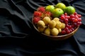 Many Thai fruits are put together in a wooden bowl on a black