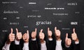 Many thumbs up with the word `thank you` in many languages in front of a blackboard