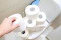 Many toilet paper rolls at home of hoarder, buying too much of hygienic means during pandemia, a hand holding a roll of