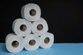 Many toilet paper rolls stacked in pyramid shape. Soft hygienic paper. Wooden table on black background Royalty Free Stock Photo