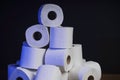 Many toilet paper rolls stacked in pyramid shape. Soft hygienic paper. Wooden table on black background Royalty Free Stock Photo