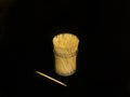 Many toothpicks are in a clear cylindrical plastic box