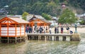 Many tourists are standing in line for taking photo of Miyajima Torii.