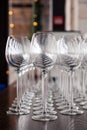 Many transparent crystal wine glasses stand in row on the brown wooden shelves of the rack. Side view. Concept of tasting, banquet Royalty Free Stock Photo