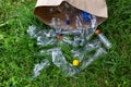 Many transparent empty water bottles are gathered in the paper bag on the green grass. Royalty Free Stock Photo