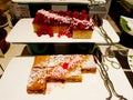 Many type of sweet cake buffet on white plate or dish with stainless steel tongs at hotel.