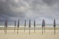 Many umbrellas on the sandy beach Background sea and black rain clouds