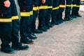 Many unrecognizable firefighters lined up in reflective pants