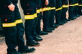 Many unrecognizable firefighters lined up in reflective pants