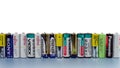 Many used and damaged primary and secondary batteries from different manufacturers stand in a row