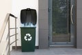 Many used plastic bottles in trash bin near entrance outdoors. Recycling problem Royalty Free Stock Photo
