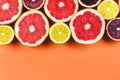 Many variety citrus fruits in a row flat lay in sunlight on orange background. Summer design template, space for text