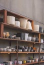 Many various terracotta plant pots on wooden shelf beside the old gypsum board wall in vintage tone style Royalty Free Stock Photo