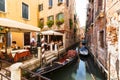 Many visitors in typical tiny cafe in Venice near canal with gondolas and boats Royalty Free Stock Photo