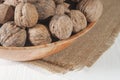 Many walnuts lie in a bowl. Bowl on burlap. White wooden table.