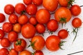 Many wet red tomatoes with stalks on white wood board from abov